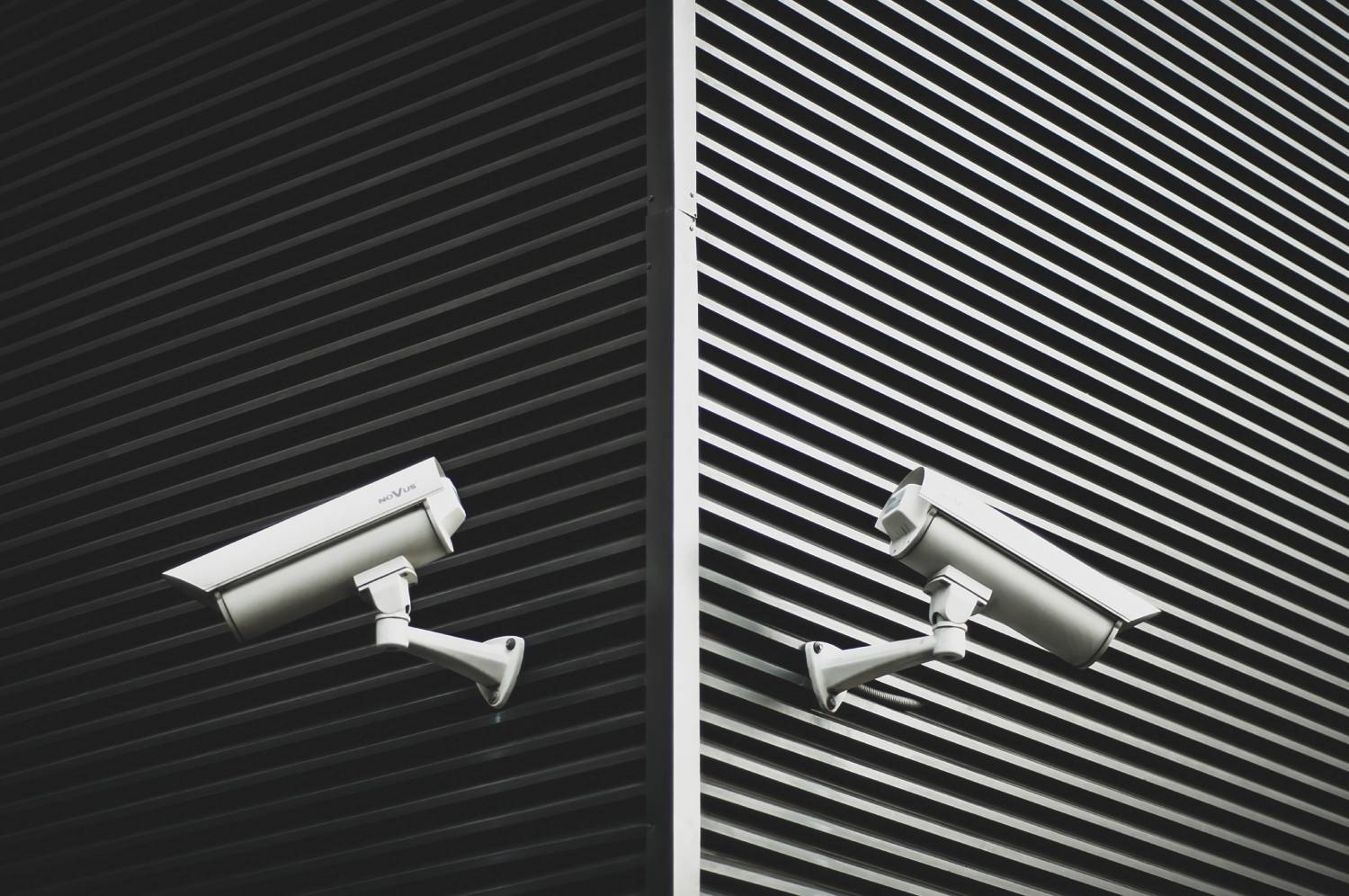 outdoor surveillance cameras on facade of building against closed metal gate