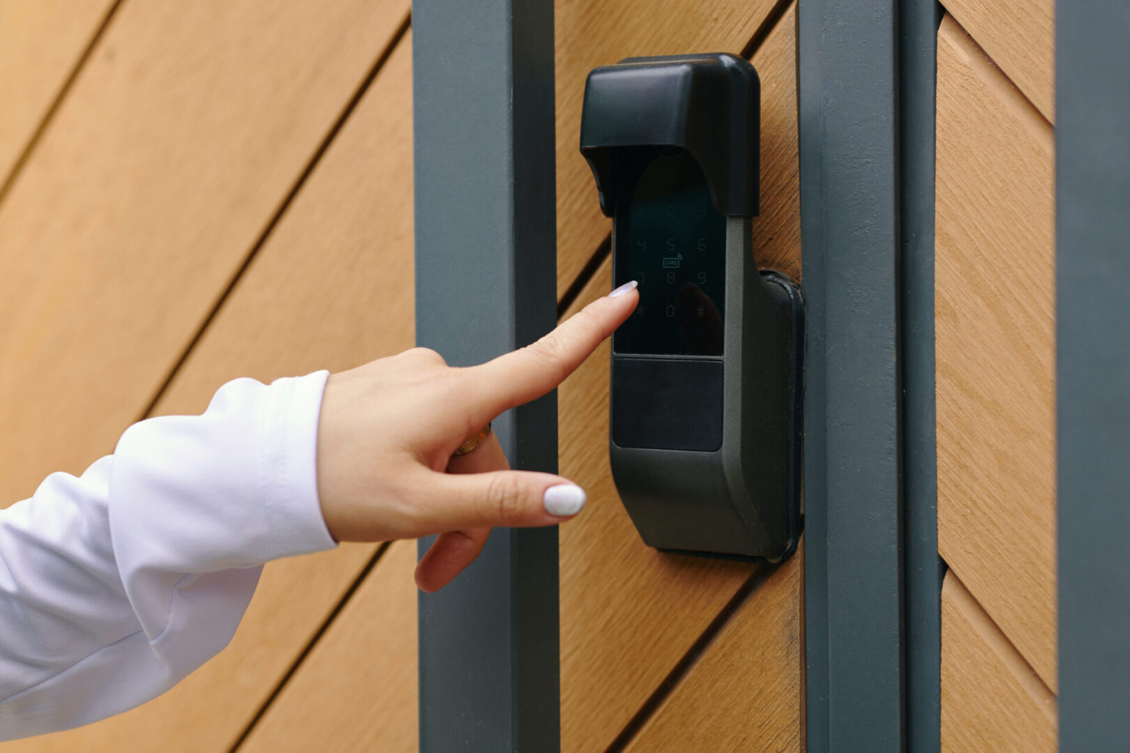Finger pressing modern digital door lock on wooden gate for secured entry. Security technology contributing to safer living environments