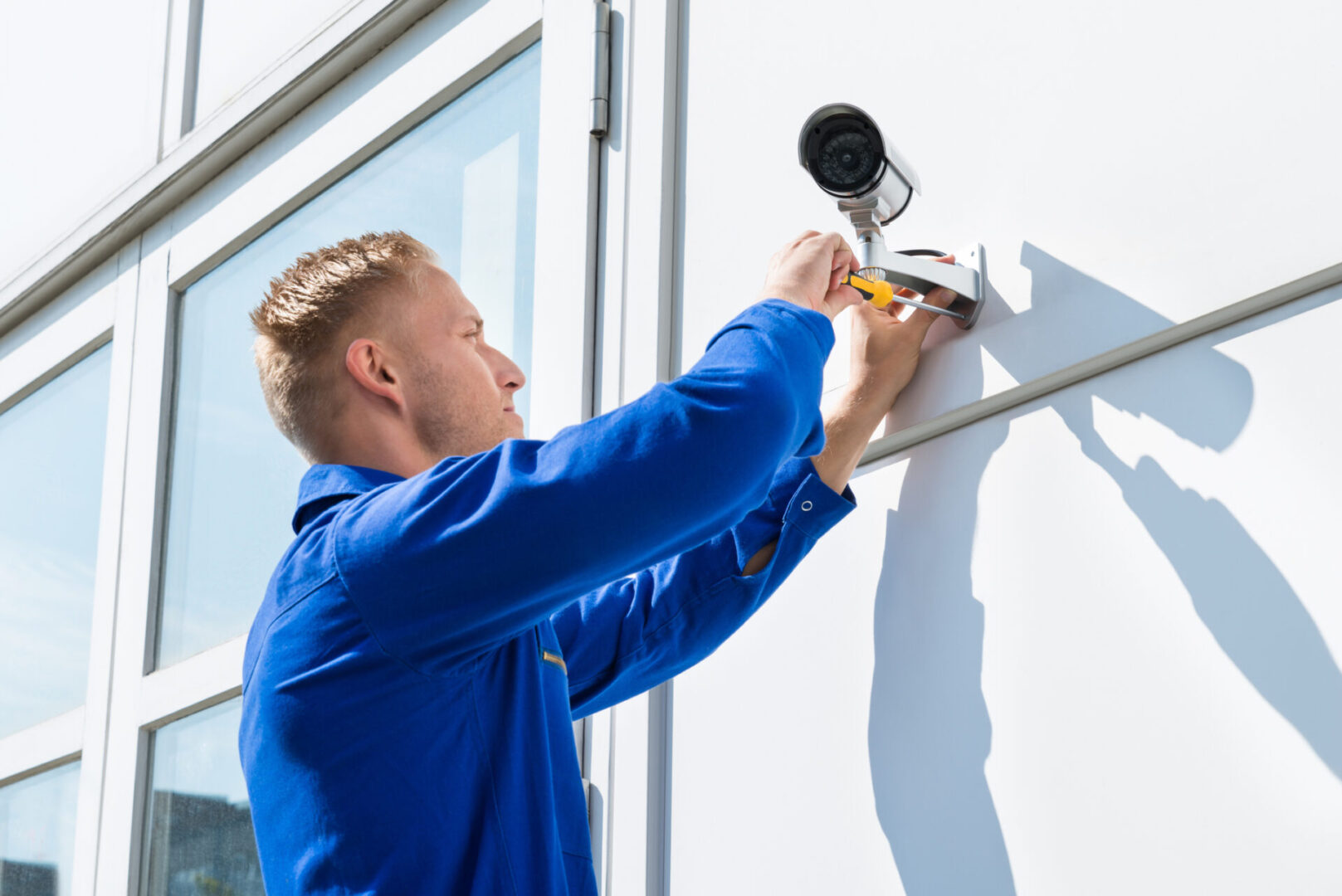 Technician Fixing Camera On Wall With Screwdriver